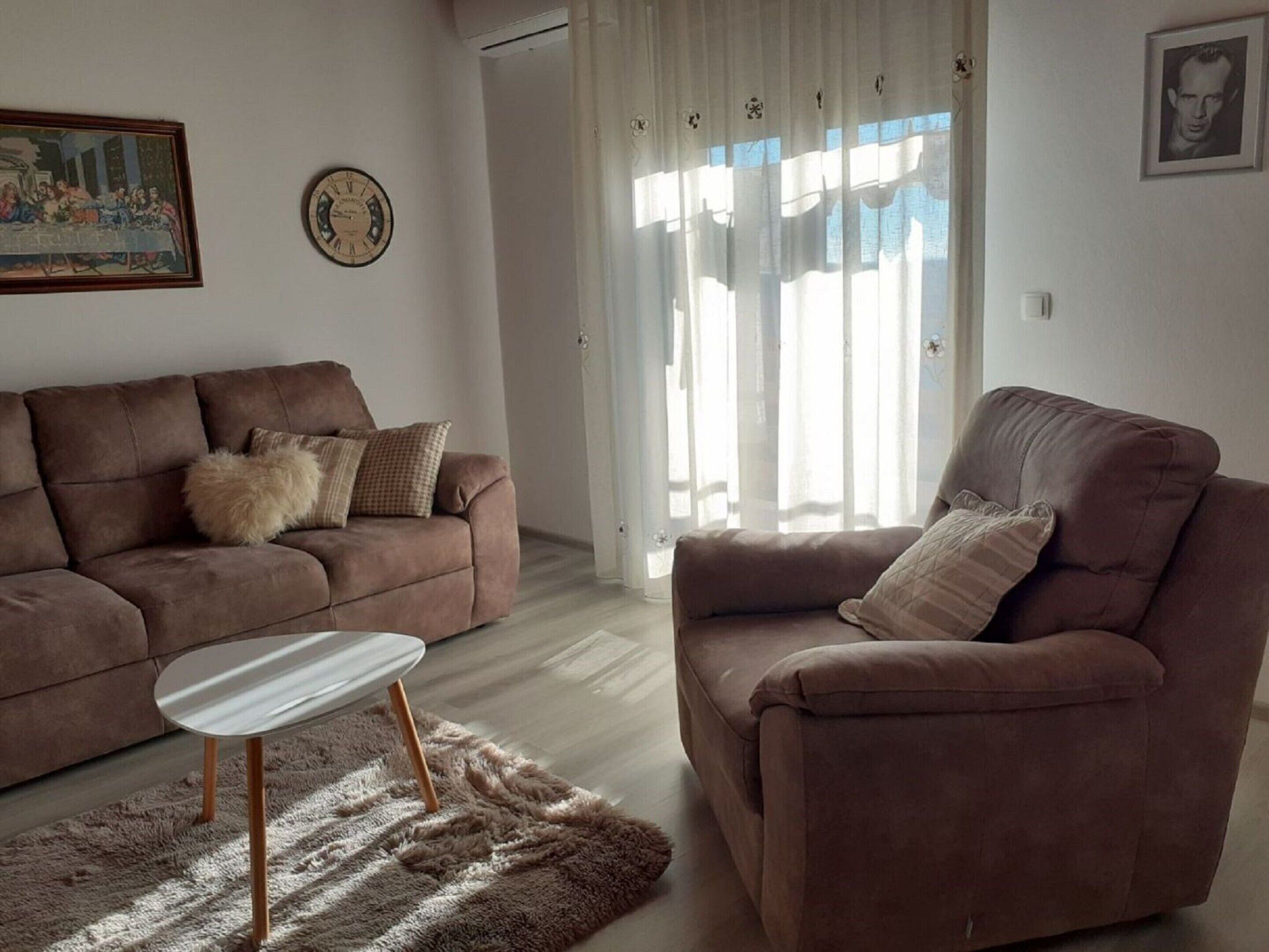 A living room with a brown sofa, a white coffee table, and a fluffy rug.
