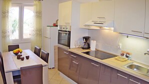 A modern kitchen with a dining area, featuring a refrigerator, oven, coffee maker, and a sink. - Apartment in Valbandon With Terrace (Fazana)