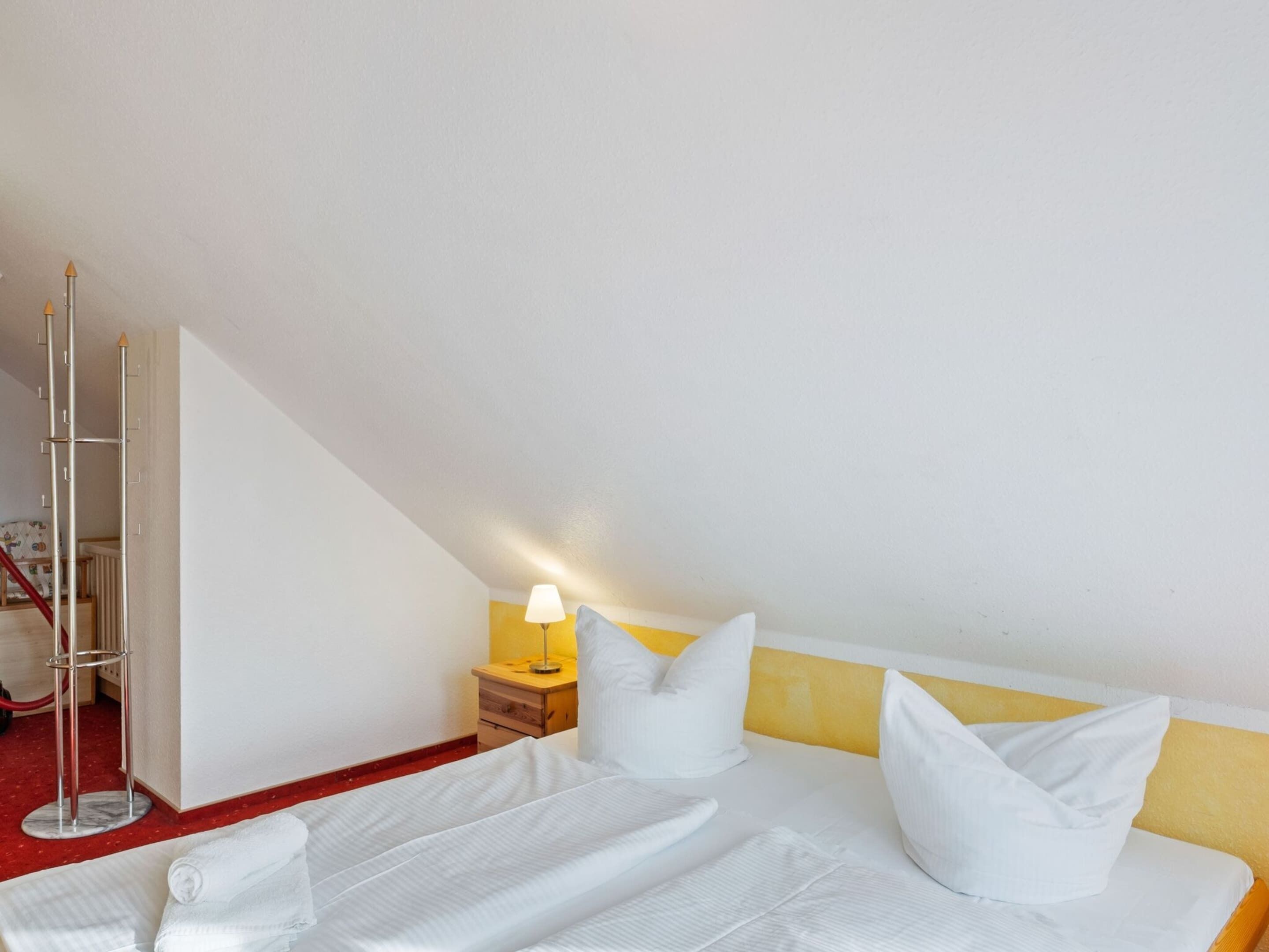A bedroom with a bed, pillows, a nightstand, a lamp, and a tall floor lamp.