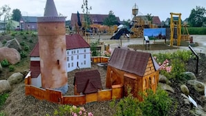 A model village with a prominent tower, a white building, and a wooden house surrounded by greenery and rocks. - Restful Holiday Home in Kalkhorst near Beach & City Center (Kalkhorst)