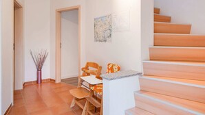 A hallway with a wooden staircase, a small table with a chair, and a vase with branches. - Restful Holiday Home in Kalkhorst near Beach & City Center (Kalkhorst)