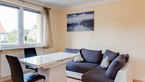 A modern living room with a white desk, black chair, and grey sofa with cushions. - Restful Holiday Home in Kalkhorst near Beach & City Center (Kalkhorst)