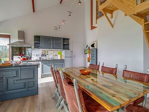 Une cuisine moderne avec des meubles de couleur grise, une table à manger en bois et un îlot central intégré.