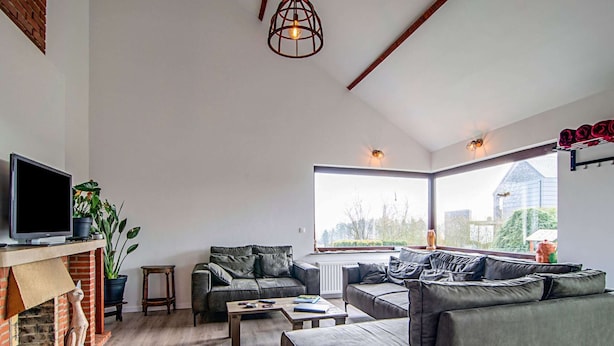A modern living room with a fireplace, leather sofas, a television, and large windows offering a view of the outside. - The Waltz of the Chickadees in Somme Leuze (Somme-Leuze)