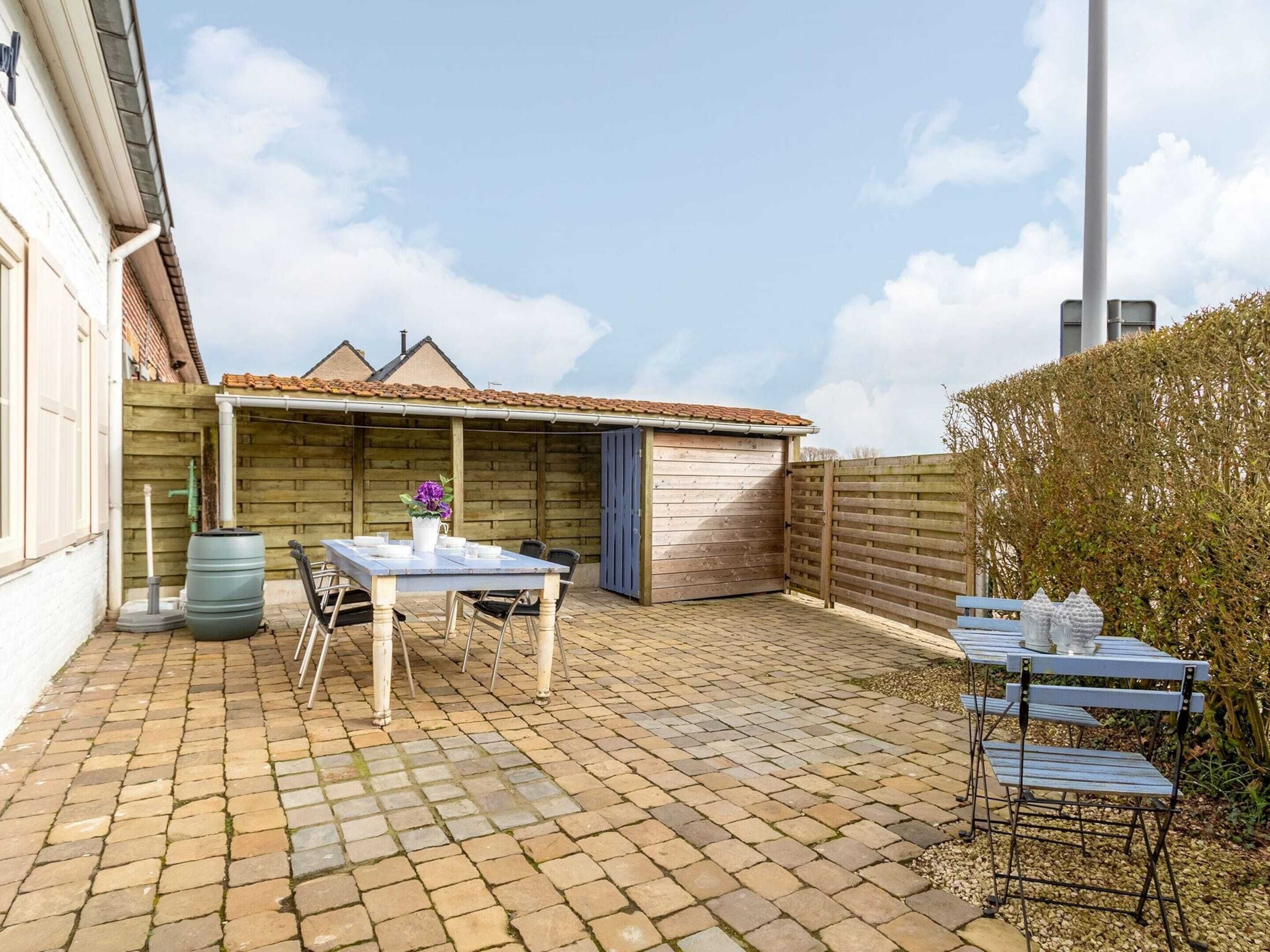 A patio area with a table and chairs, a wooden fence, and a garage.