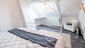 A bedroom with a bed, a chair, a radiator, and a skylight. - Holiday Home in Stavele With Terrace (Alveringem)