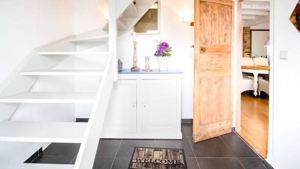 A staircase leading to a landing with a white cabinet and a wooden door. - Holiday Home in Stavele With Terrace (Alveringem)