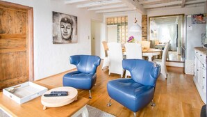 A modern living room with two blue leather chairs, a wooden coffee table, and a Buddha painting on the wall. - Holiday Home in Stavele With Terrace (Alveringem)