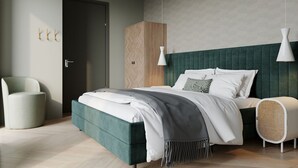 A modern bedroom with a large bed, a bedside table, a chair, and a wardrobe. - Luxury Villa With Sauna Near the Beach (De Cocksdorp)