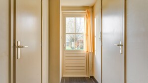 A hallway with two doors, a window with curtains, and a tiled floor.