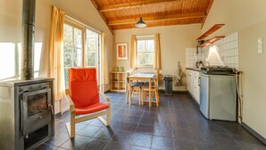 A cozy kitchen with a wood stove, a dining area with a table and chairs, and a kitchen counter with appliances.