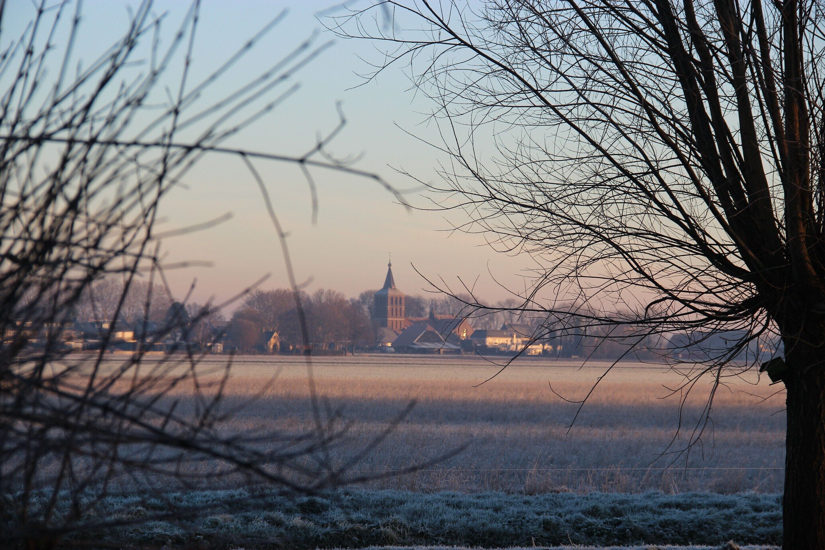 A frosty field with a church and buildings in the background.