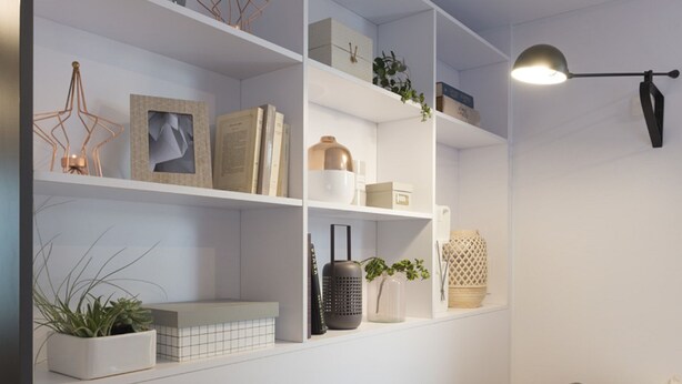 Un salon moderne avec des étagères blanches, un canapé gris et un lampadaire noir.