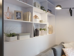 Una sala de estar moderna con estanterías blancas, un sofá gris y una lámpara de pie negra.