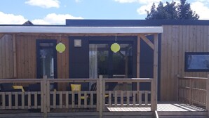 Une cabane en bois dotée d’un porche couvert, d’une petite terrasse et d’une fenêtre offrant une vue sur le ciel.