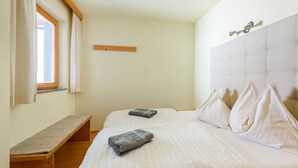 A bedroom with a bed, a bench, a window, and a headboard. - Apartment in Aschau Near Kaltenbach Ski Lift (Aschau Im Zillertal)