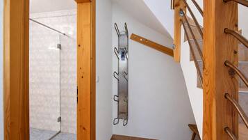 A wooden staircase with a metal handrail and a metal rack attached to the wall.