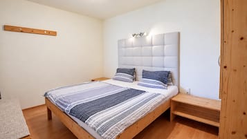 A bedroom with a wooden bed, a headboard with built-in lighting, and a wooden nightstand.