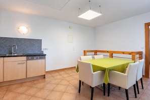 A compact kitchen with a dishwasher, a sink, and a countertop. There is a dining area with a table and chairs, and a ceiling light fixture. - Apartment in Aschau Near Kaltenbach Ski Lift (Aschau Im Zillertal)