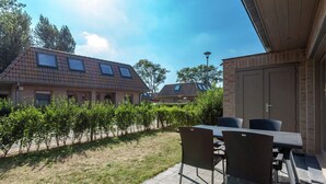 Un espace patio avec une table et des chaises, un mur en briques et une vue sur les maisons voisines.