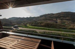 Un balcon donnant sur une route et des collines.