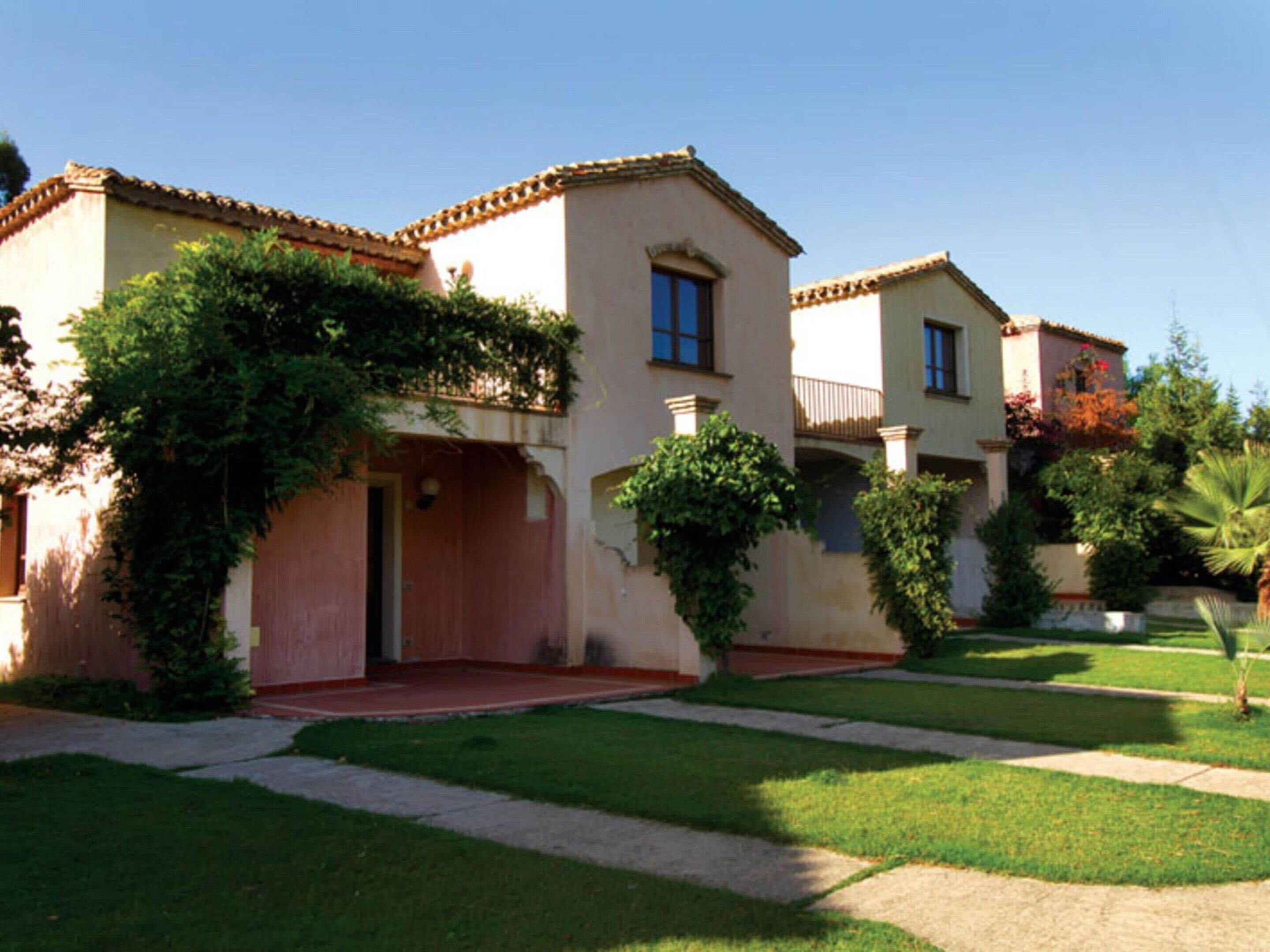A two-story building with a red-tiled roof, a covered entrance, and a well-maintained lawn.