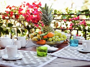 A table set with a fruit bowl, teapots, cups, and a glass. - Apartment in Sardinia Near Stunning Beaches (Pula)