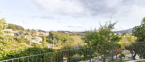 A fenced outdoor area with a bench and a table, overlooking a residential area with houses and greenery.