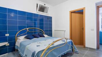 Une chambre à coucher avec un lit, une fenêtre, un radiateur et une porte.