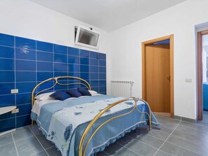 A bedroom with a bed, a window, a radiator, and a door.
