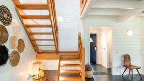 Een modern interieur met een houten trap, een schommelstoel en een wand versierd met gevlochten manden.
