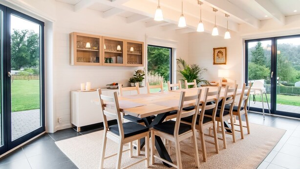 Een moderne eetruimte met een grote houten tafel, zes stoelen en hanglampen.