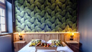 A hotel room with a bed, two nightstands, a tray of breakfast items, and a fern-patterned wall. - Nice Cottage in a Castle-farm in Ohey With Swimming Pond (Ohey)