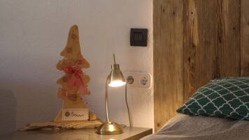 Cabecera de madera, lámpara de noche, una figura decorativa de madera y un cojín estampado.