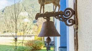 Eine Glocke mit Hirschfigur an einer Wand angebracht, vor einer Berglandschaft.