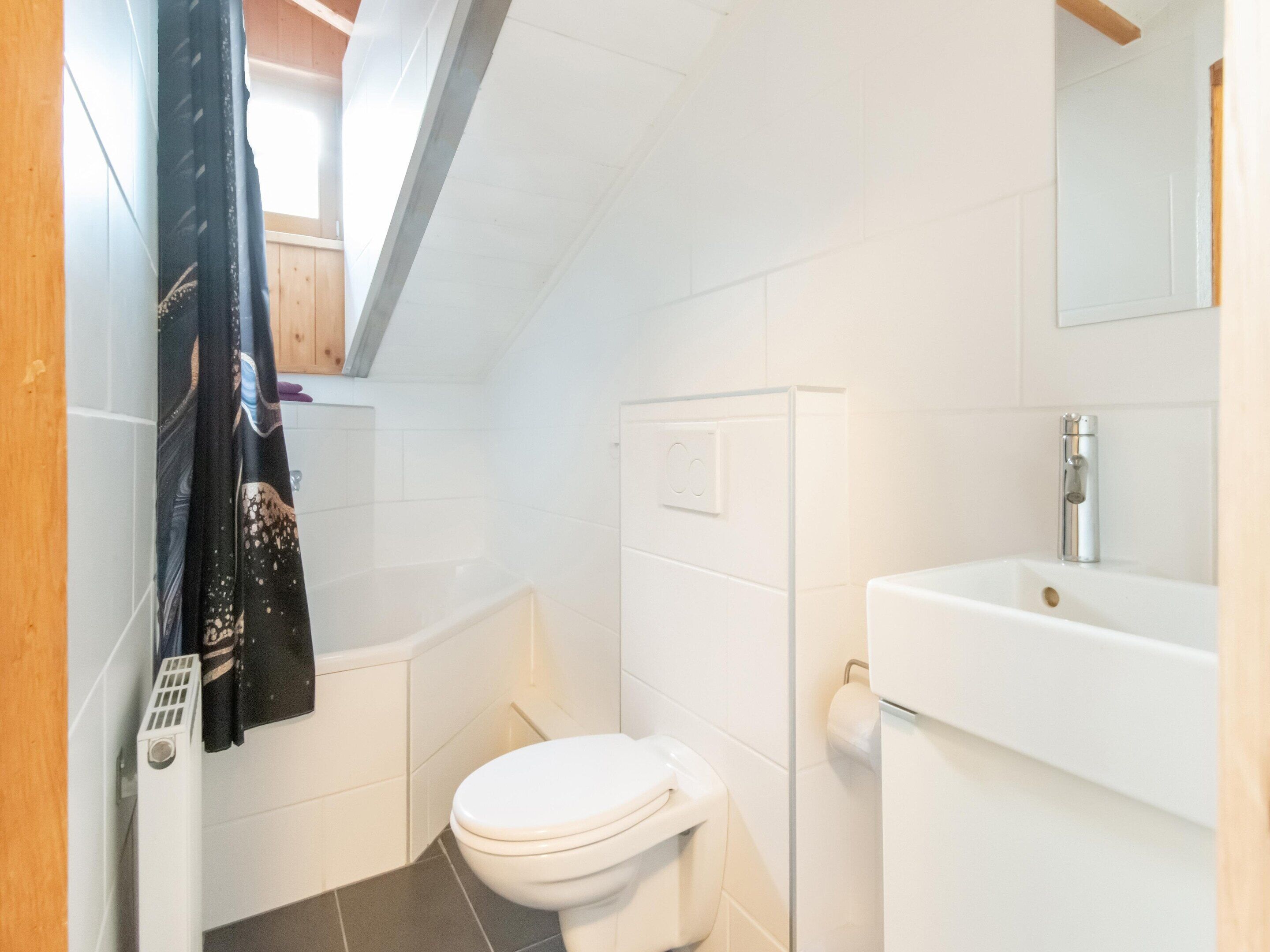 Une petite salle de bain moderne avec des toilettes blanches, un lavabo blanc et une douche.