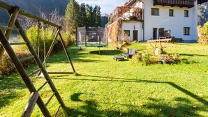Ein Haus mit Balkon, Schaukel und Trampolin im Garten.