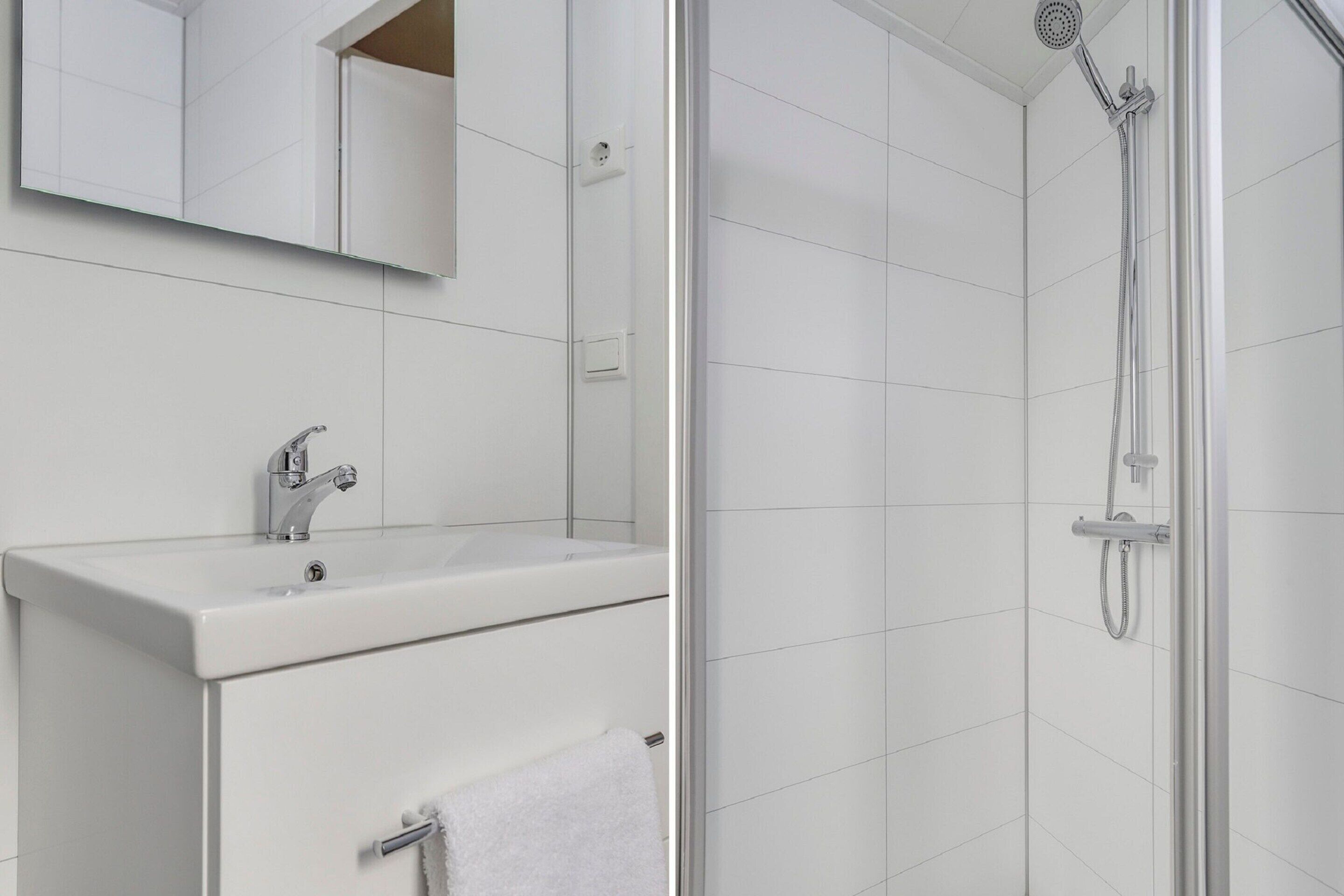 Un baño con lavamanos blanco, espejo y ducha.