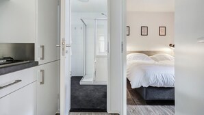 A modern hotel room with a bed, a shower area, and a kitchenette. - Chalet by Forest Edge With Modern Design (Markelo)
