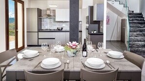 Een moderne eetruimte met een marmeren tafel, witte stoelen en een glazen vaas met bloemen.