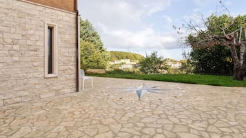 Une cour avec un sol en pierre, une boussole et une chaise blanche.