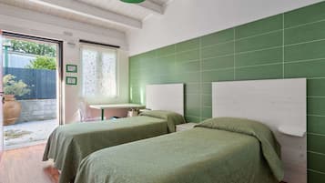 Une chambre avec deux lits, une petite table et une fenêtre donnant sur l’extérieur.