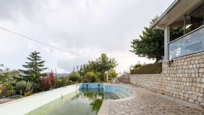 En swimmingpool med en mur av sten och ett område runt poolen som är belagt med plattor.
