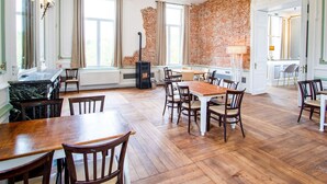 A spacious dining area with wooden tables and chairs, a brick wall, and large windows. - Castle With Wellness and Cinema (Gesves)