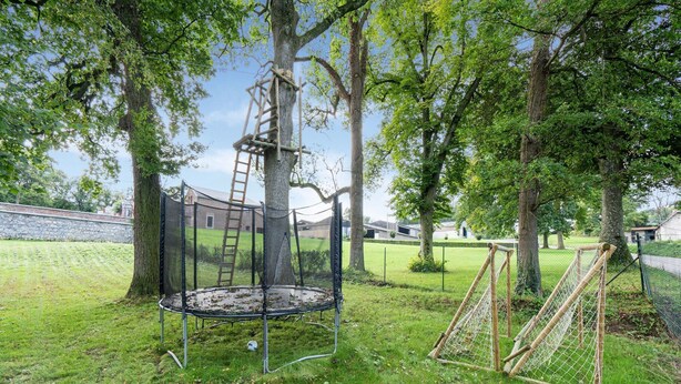A playground with a trampoline, a climbing structure, and a swing set. - Castle With Wellness and Cinema (Gesves)