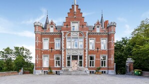 A large, historic building with a symmetrical facade, multiple windows, and a central entrance. - Castle With Wellness and Cinema (Gesves)