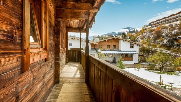A wooden balcony with a view of a snow-covered landscape and houses in the background. - Chalet in Jochberg Near Thurn Pass (Jochberg)