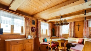 A cozy cabin interior with wooden walls and ceiling, a dining area with a bench, and a cross on the wall. - Chalet in Jochberg Near Thurn Pass (Jochberg)