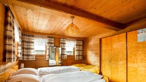 A wooden cabin room with a bed, a mirror, and a wardrobe. - Chalet in Jochberg Near Thurn Pass (Jochberg)