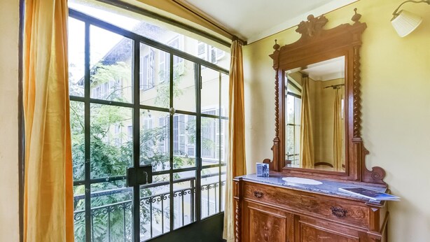 Een kamer met een groot raam, een houten dressoir en een spiegel.
